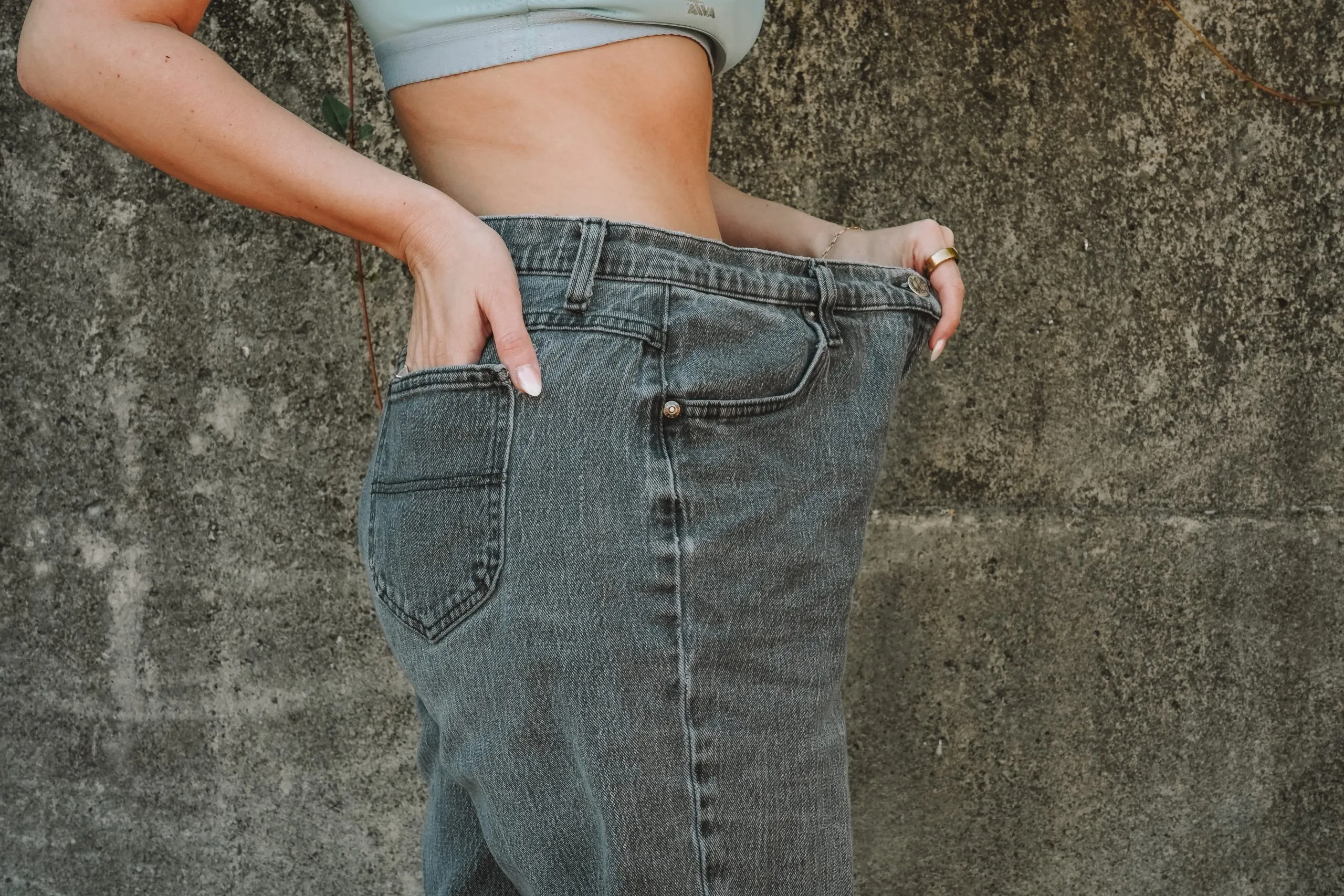 Woman showing loose-fitting jeans around waist, symbolizing weight loss — ideal for showcasing a comparison between Semaglutide vs. Tirzepatide and discussing medical weight loss options.