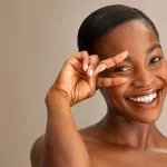 Woman with a peace sign near her eye representing under-eye rejuvenation with Greenwich Medical Spa