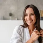Smiling woman in a spa setting, representing bioidentical hormones vs traditional HRT, highlighting hormone therapy options like pellets, creams, and injections with a focus on personalized, monitored care from Greenwich Medical Spa.