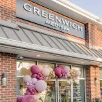Exterior storefront of Greenwich Medical Spa featuring modern med spa signage and balloon arch decoration, illustrating what a med spa offers and the benefits of a medically led med spa.