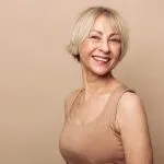 Smiling mature woman at Greenwich Medical Spa representing how the face ages over time, common aging face stages, and personalized facial aging treatments.