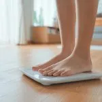 Greenwich Medical Spa guidance for a weight loss plateau, featuring a person stepping on a scale while addressing stalled weight loss and semaglutide maintenance.